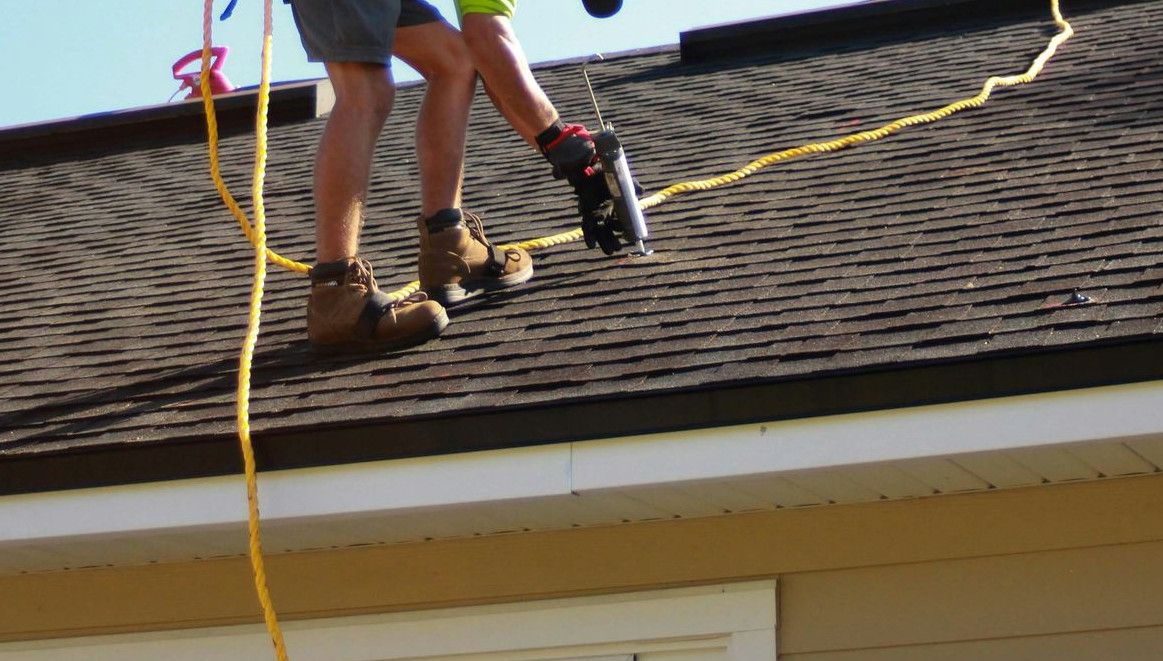 a man working on a roof with a power drill